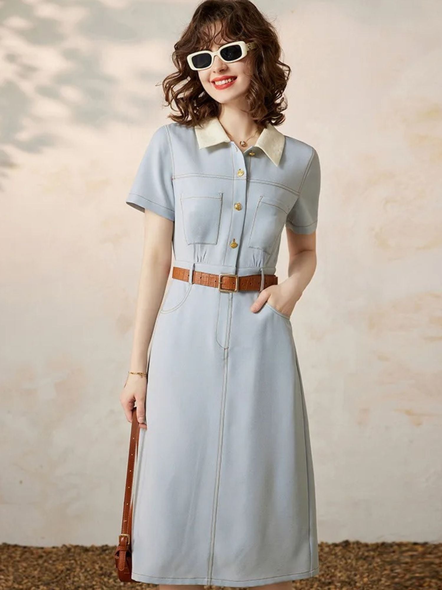 Front view of blue collared dress with gold buttons and belted waist.