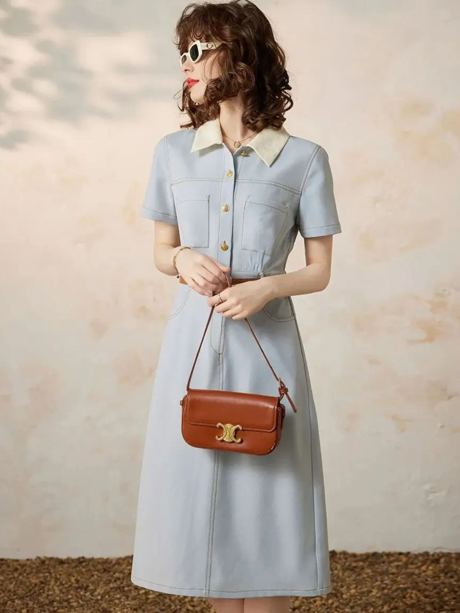 Angled view of light blue button-up dress with pleats and short sleeves.