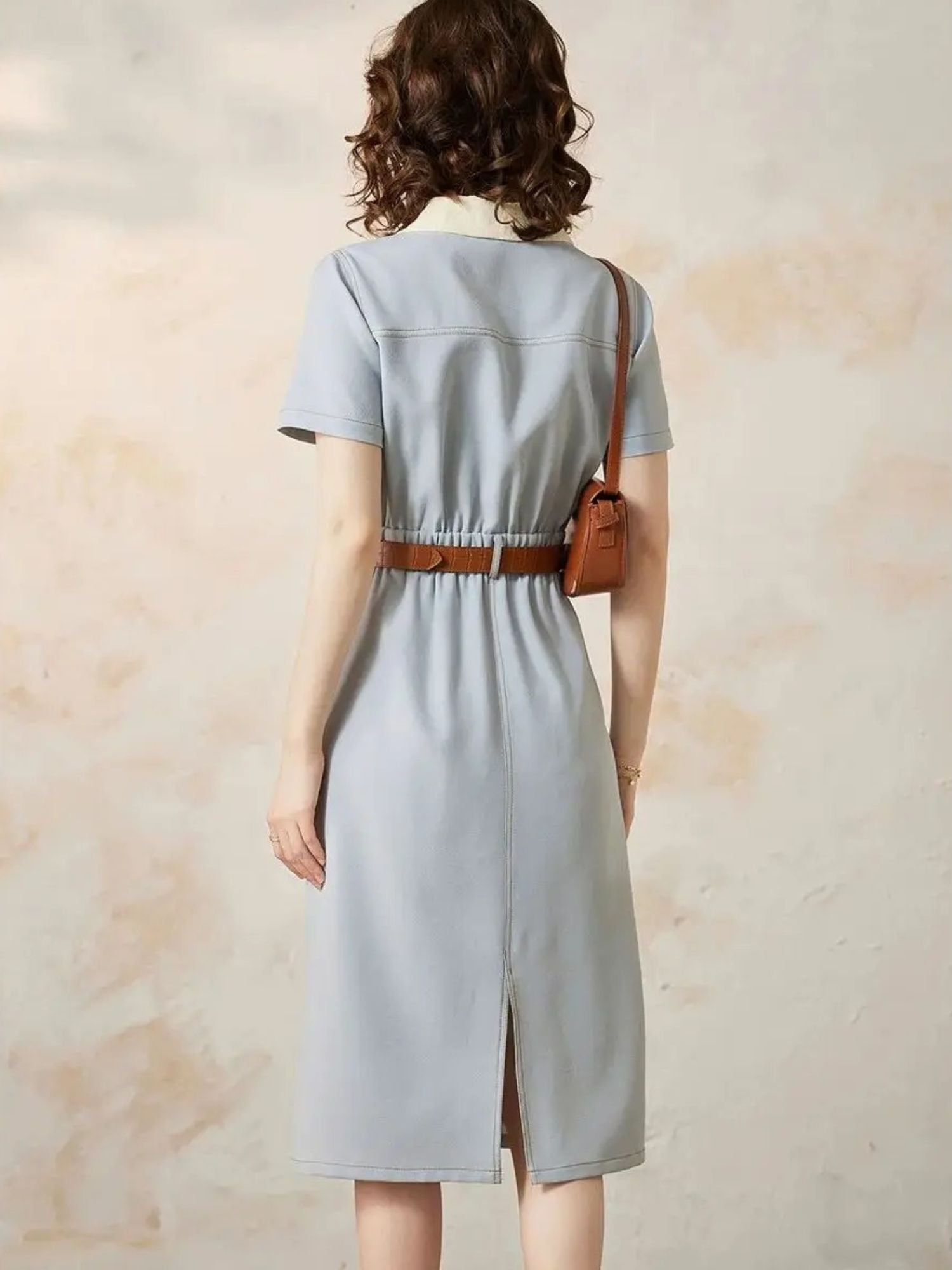 Back view of blue dress with brown belt and center seam.