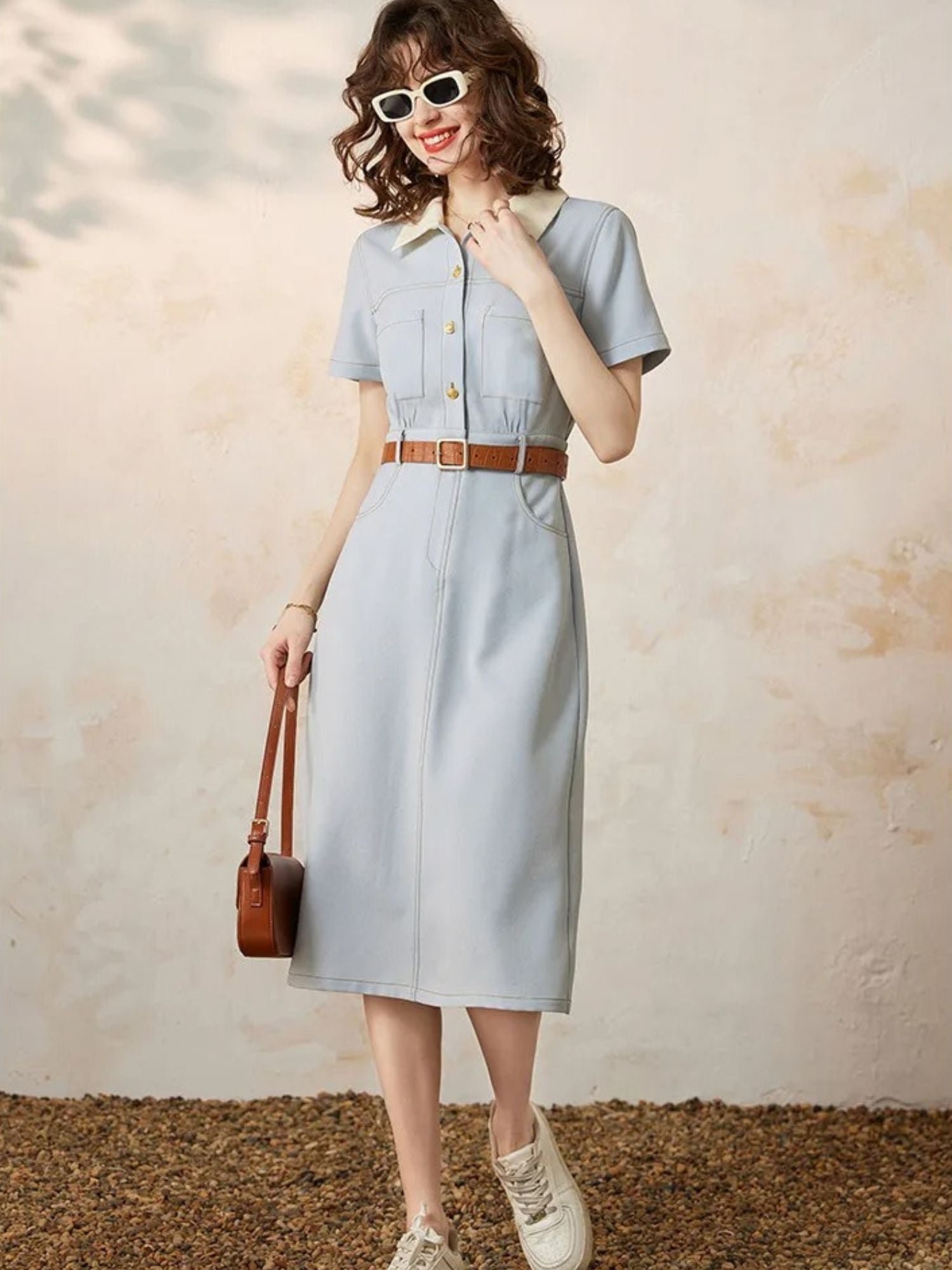 Front view of blue dress with sunglasses, brown bag, and white shoes.
