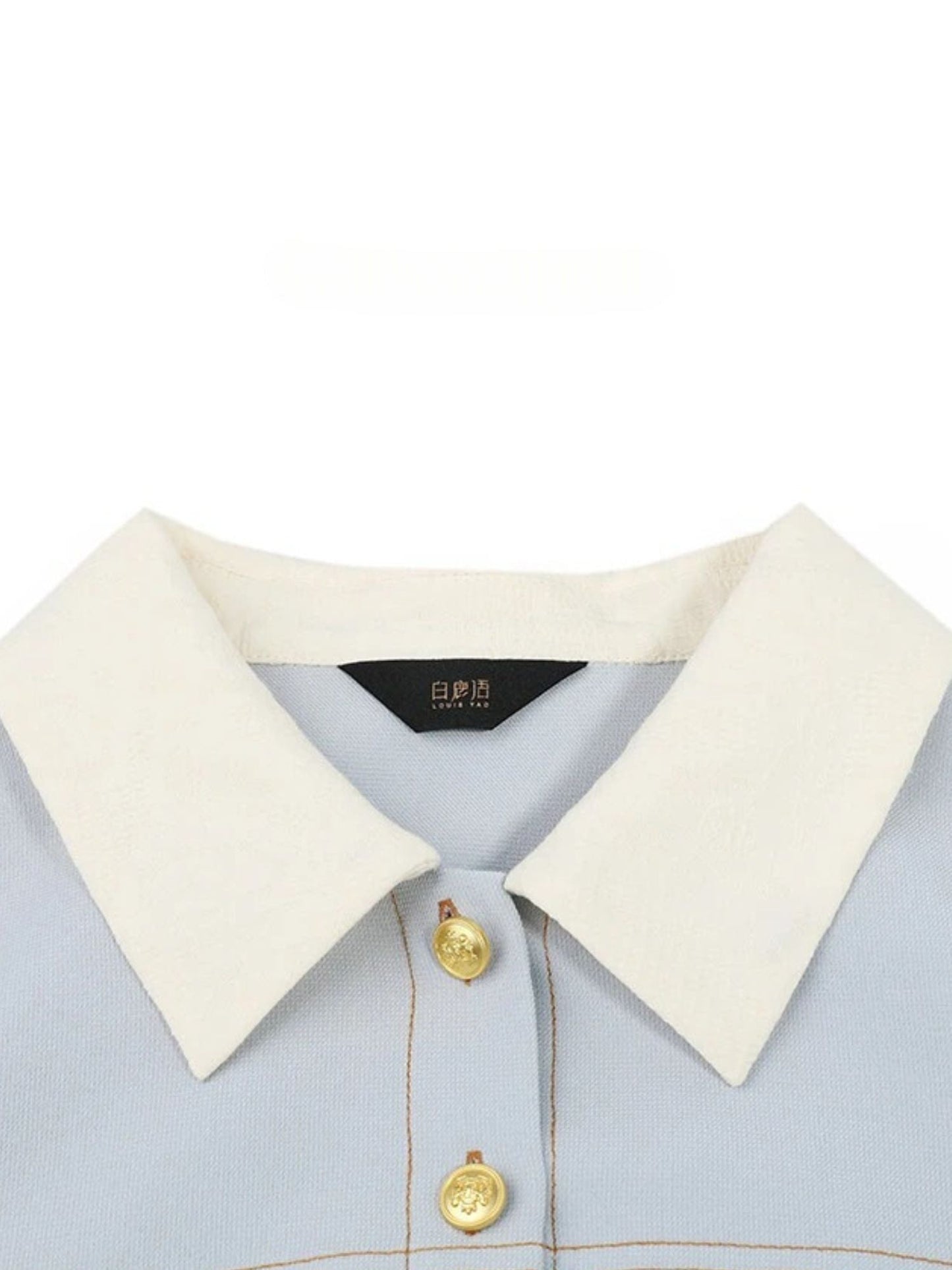 Close-up of ivory contrast collar and gold buttons on blue dress.