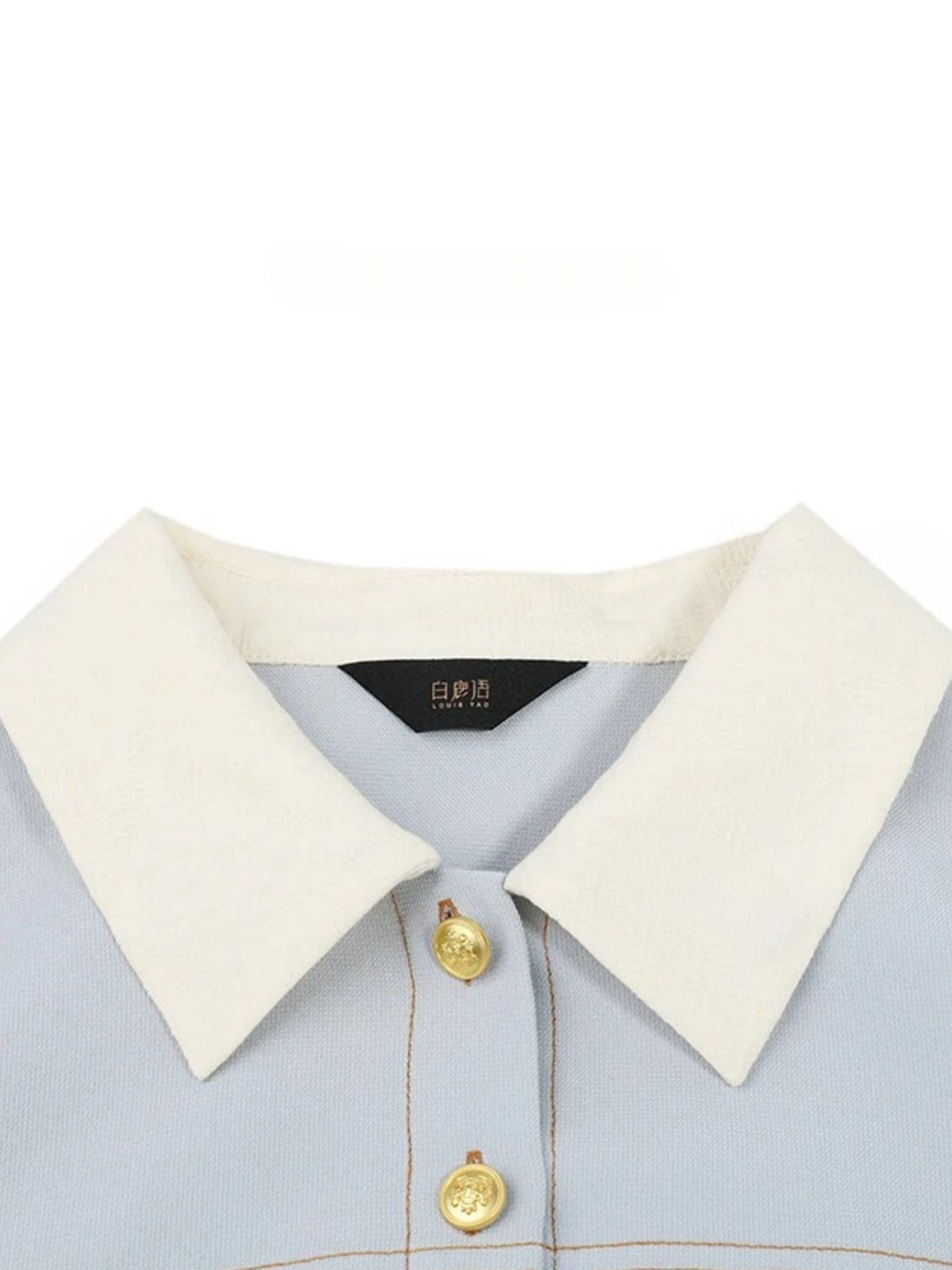 Close-up of ivory contrast collar and gold buttons on blue dress.