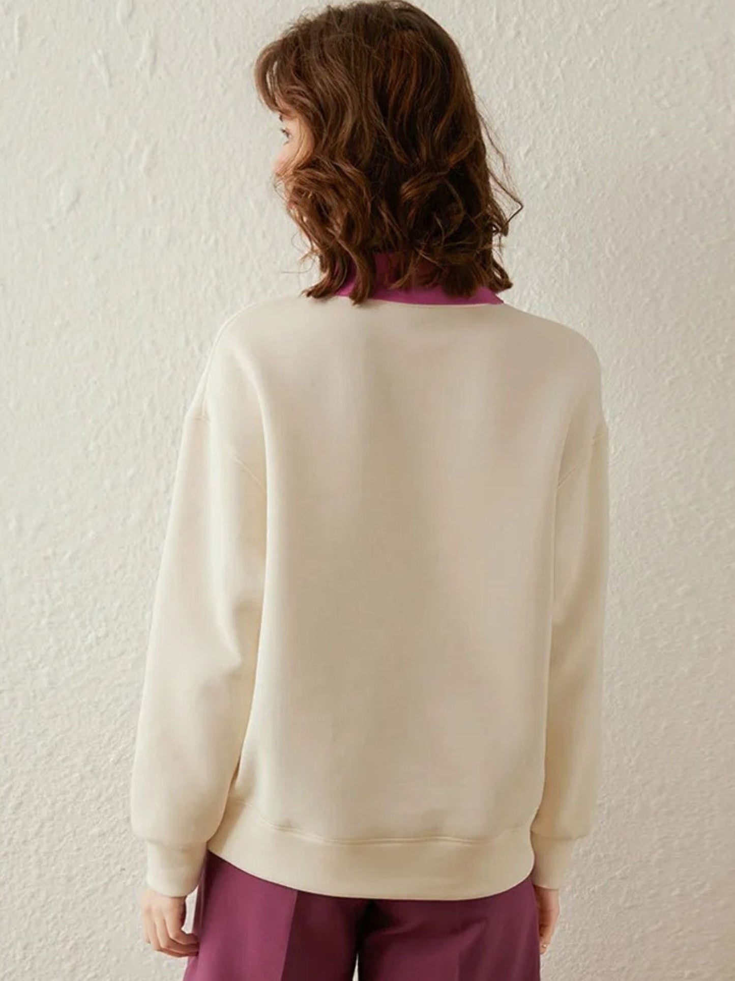 Back view of cream sweatshirt with visible pink collar accent.