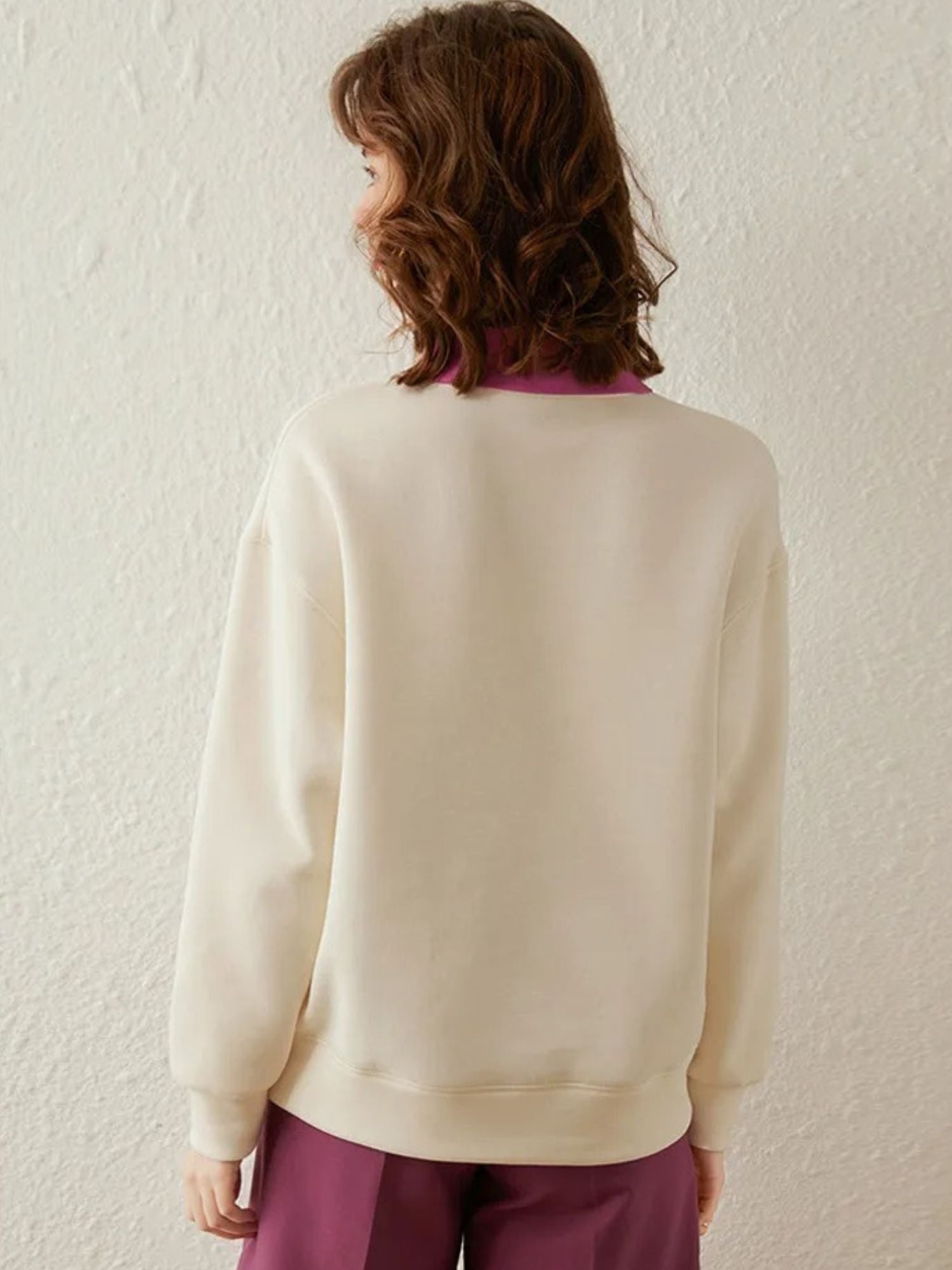 Back view of cream sweatshirt with visible pink collar accent.