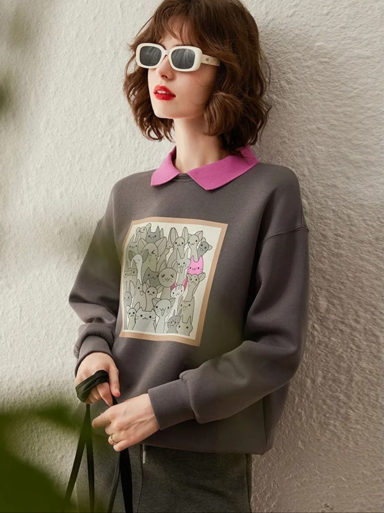 Front view of grey graphic sweatshirt with pink collar and olive skirt.