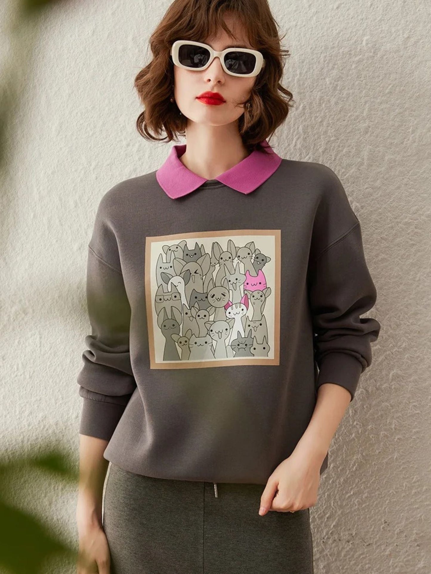 Model in grey sweatshirt with forest print, styled with white sunglasses.