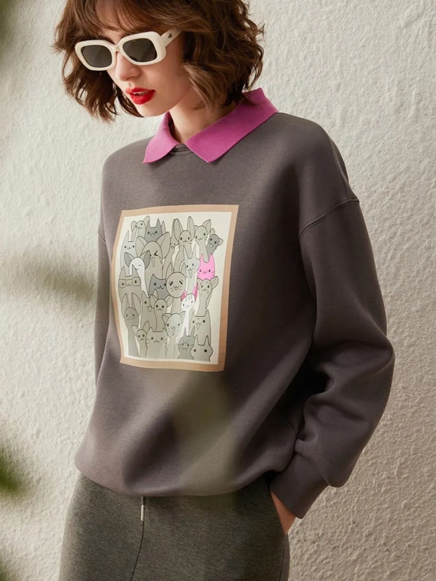 Side view of grey sweatshirt with illustrated graphic and pink collar detail.