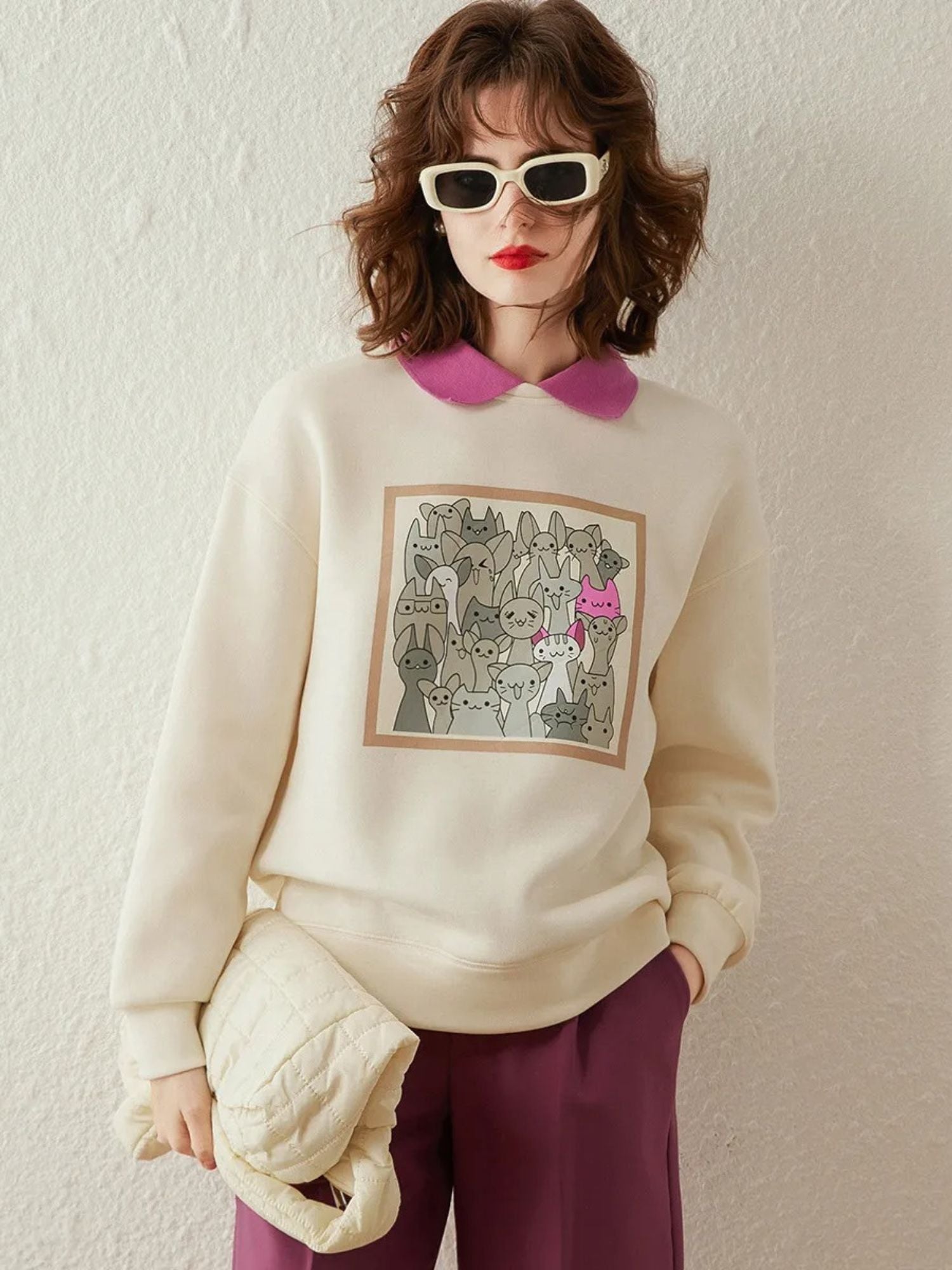 Model in cream sweatshirt with pink collar and purple mini skirt.