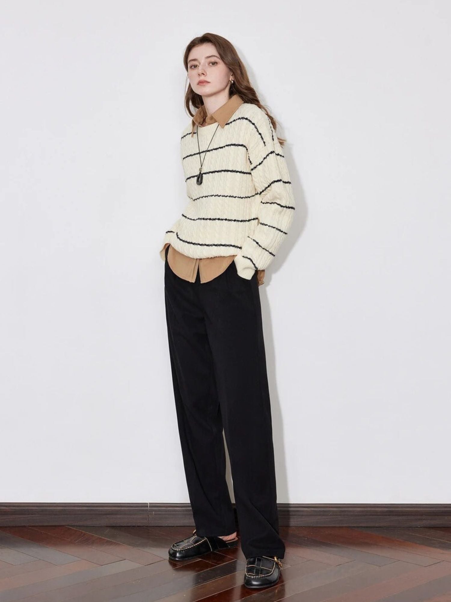 Model in black wide-leg trousers with striped sweater and brown loafers.