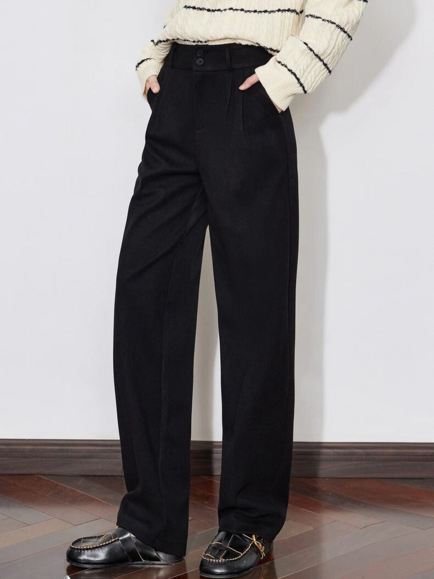 Side view of black high-waisted pants paired with a tucked sweater.
