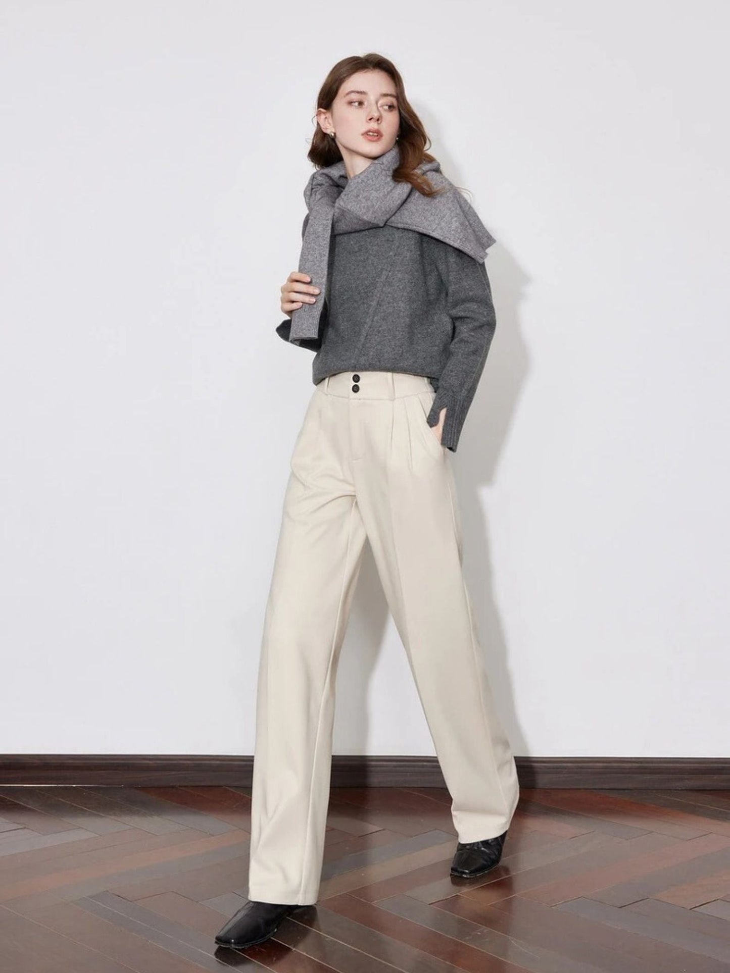 Model in beige wide-leg pants with grey knit top and black shoes.