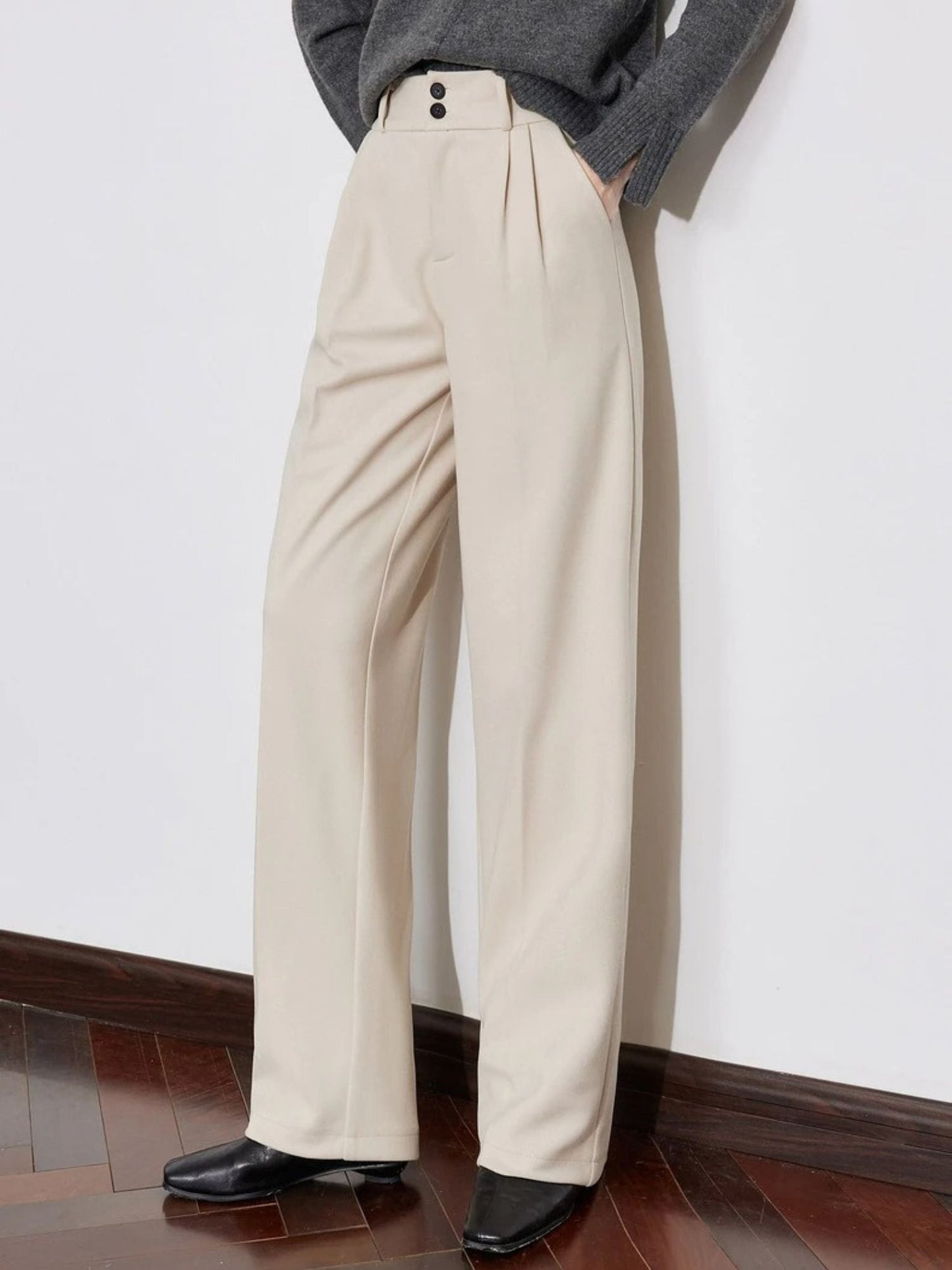 Side view of pleated beige pants with loose fit and tucked-in sweater.