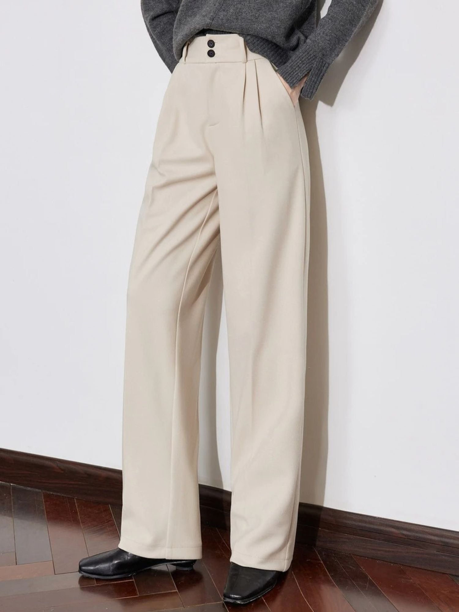 Side view of pleated beige pants with loose fit and tucked-in sweater.