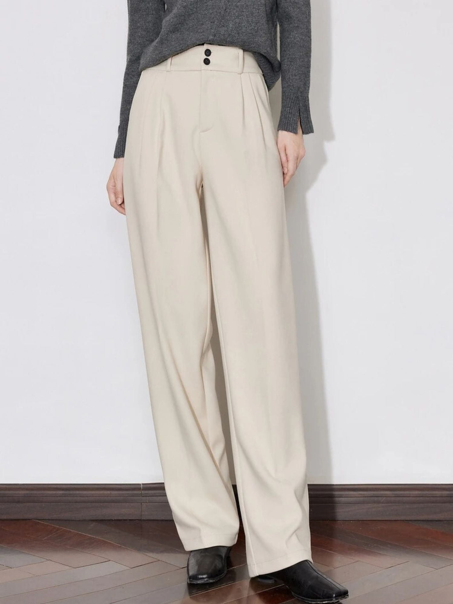 Front view of beige pants with side pockets and black button closure.