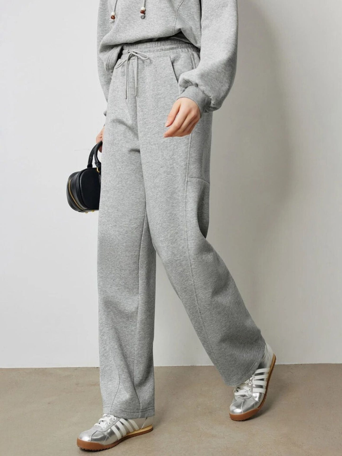 Side view of grey jogger-style pants with relaxed fit and white sneakers.