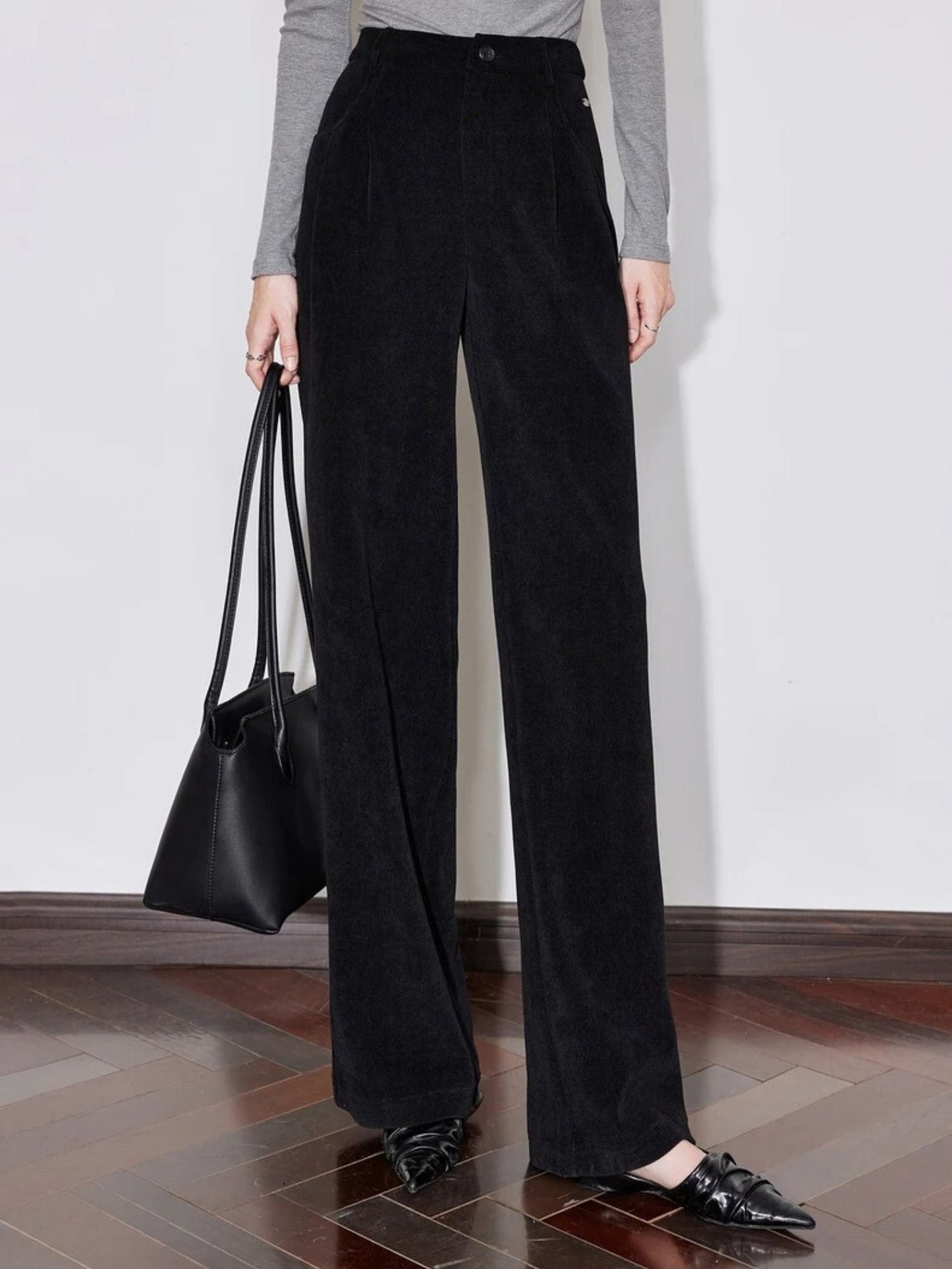 Close-up of black wide-leg trousers styled with a grey long-sleeve top.